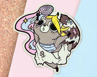 May include: A cartoon raccoon wearing a white dress with a blue and white striped pattern, holding a pink and blue lollipop. The raccoon has a yellow banana on its head and is surrounded by a pink and blue swirl.