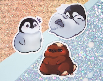 May include: Three cartoon animal stickers featuring a penguin with its wings wrapped around itself, a penguin with its eyes wide open, and a brown bear with a surprised expression.