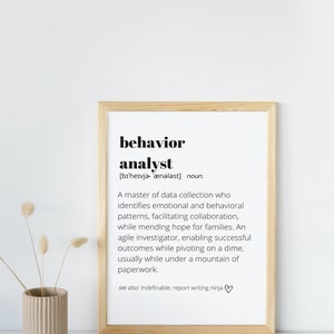 Peut inclure: Un cadre avec la définition de « analyste du comportement » en texte noir. La définition comprend la prononciation, une description du rôle et des termes connexes. Un vase beige avec des fleurs séchées est à gauche.