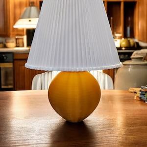 May include: A yellow table lamp with a white pleated lampshade. The lamp is sitting on a wooden table.
