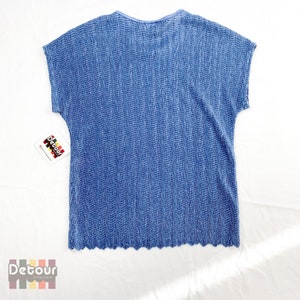 May include: A blue, short-sleeved, pleated top with a scalloped hem. The top has a simple, round neckline and a subtle, textured pattern.