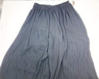 May include: A black pleated skirt made of a lightweight fabric. The skirt has a wide waistband and falls to the ankles.