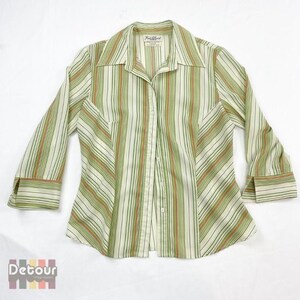 Peut inclure: Une chemise boutonnée à rayures blanches, vertes et orange avec un col et des manches longues. La chemise a une silhouette ajustée et une fermeture boutonnée. L'étiquette de la marque indique "Frank Lloyd".