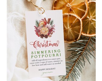 May include: A white tag with the words "Christmas Simmering Potpourri" in red and green. The tag is decorated with a watercolor illustration of dried orange slices, cinnamon sticks, and greenery. The tag also includes instructions and the phrase "Happy Holiday".