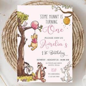 K&ouml;nnte beinhalten: Eine rosa Geburtstagseinladung mit Illustrationen von Winnie-the-Pooh-Charakteren. Die Einladung enth&auml;lt den Text "Some Hunny is Turning One" und Details f&uuml;r Amelias 1. Geburtstag, einschlie&szlig;lich Datum, Uhrzeit und Ort.