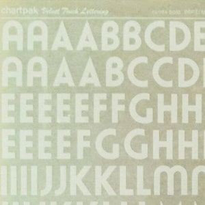 May include: Two sheets of white adhesive letters and numbers on a brown background. The letters are in a bold, blocky font. The first sheet contains the letters A through M and the second sheet contains the letters P through Z, the ampersand, and the numbers 1 through 9.