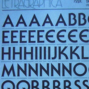 以下が含まれることがあります： 太字のセリフゴシックフォントのLetraset転写文字のシート。シートは青色で、黒色の大文字、数字、記号が記載されています。シートの上部には「Letraset」と「72pt. Serif Gothic Bold ITC.」のテキストが印刷されています。