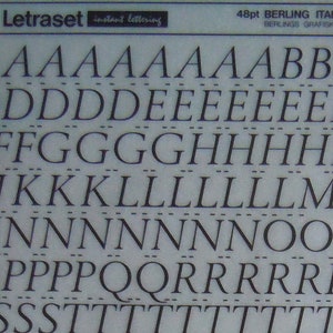 May include: A sheet of Letraset instant lettering in the Berling Italic font. The sheet includes the alphabet in uppercase, numbers, and symbols. The font is a classic italic typeface with a slightly slanted appearance. The sheet is printed on a white background with black lettering.