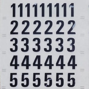 May include: A sheet of black transfer lettering featuring the numbers 0 through 9 arranged in multiple rows and columns. The top of the sheet displays the text ANORMA, Univers 67, letter-press, and 67-60.CH. The bottom includes the codes 67 60 and 67 60 0630.