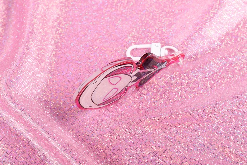 May include: Pink and white plastic keychain shaped like a cartoon character with a white metal clasp.