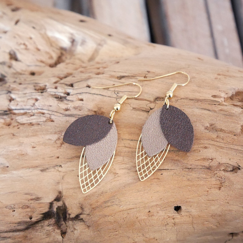 May include: A pair of gold tone earrings with brown and beige leather leaf shapes and a gold wire mesh design.