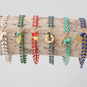 Peut inclure: Six bracelets en chaîne dorée avec des perles émaillées de différentes couleurs et des breloques. Les breloques comprennent une feuille, une étoile, un cercle, une feuille avec des perles turquoise et un cercle avec une perle dorée.