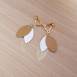 May include: A pair of gold tone clip-on earrings with a layered design. The earrings feature two brown and white leaf shapes with a gold wire mesh pattern.