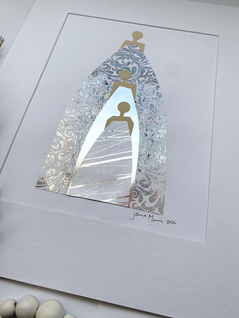 May include: A silver and gold abstract art print featuring three figures in a layered design. The figures are outlined in gold and the background is a silver damask pattern. The print is signed "Jenna Mani 2022".