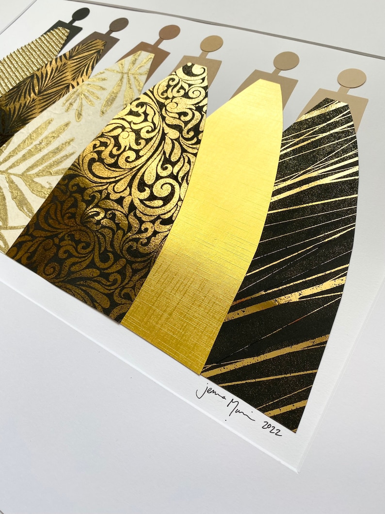May include: A framed art print featuring a collage of gold and black patterned paper cut into the shape of five figures. The print is signed "Jemma Nunn 2022".