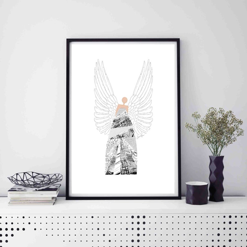 May include: Black and white print of an angel with wings, wearing a patterned dress. The print is framed in a black frame and is hanging on a white wall.