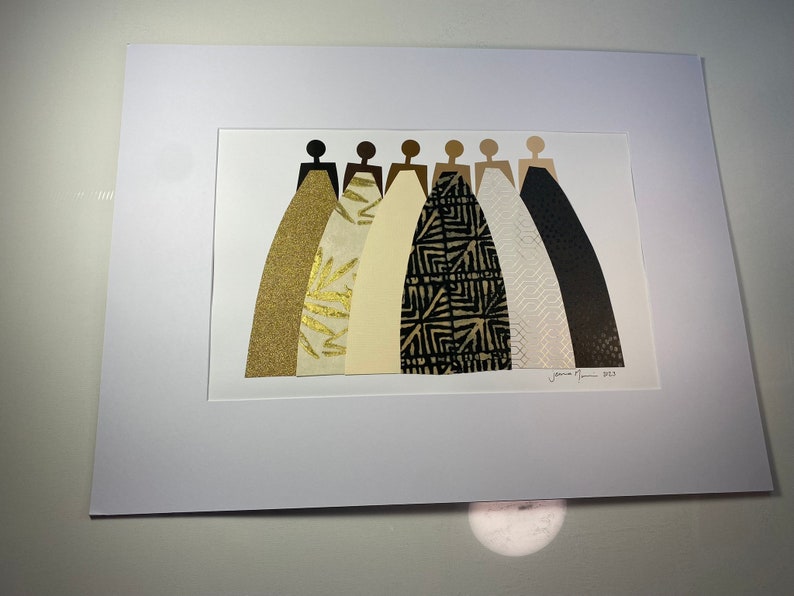 K&ouml;nnte beinhalten: Ein gerahmter Druck eines Collages aus sieben Figuren in schwarzen Silhouetten, die Kleider aus verschiedenen gemusterten Papieren tragen. Die Kleider sind in Gold-, Creme-, Schwarz- und Wei&szlig;t&ouml;nen gehalten. Der Druck ist signiert mit "Jamie Morris 2023".