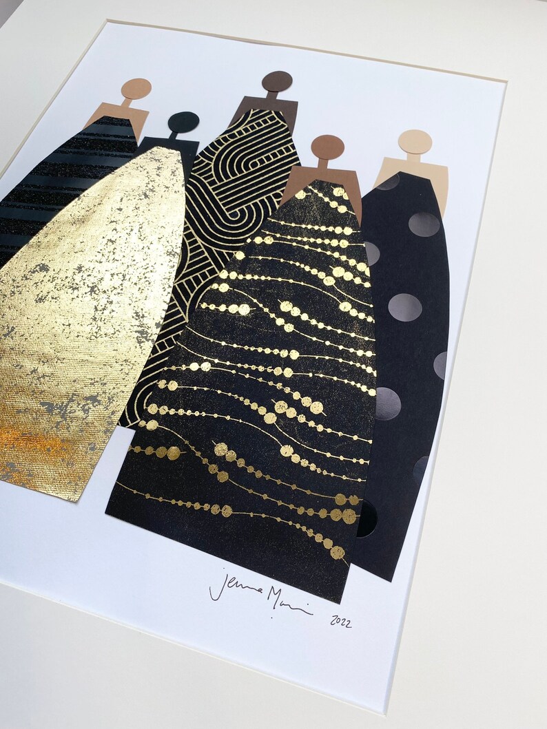 May include: A framed collage of five figures in black and gold dresses. The dresses are made of different patterned paper, including polka dots, geometric shapes, and a gold foil design. The figures are cut out of brown paper and have no facial features. The artwork is signed "Jenna Mani 2022" in the bottom right corner.
