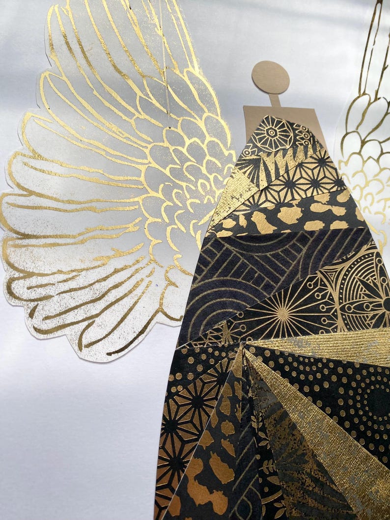 May include: A gold and black paper angel with geometric patterns against a white background.