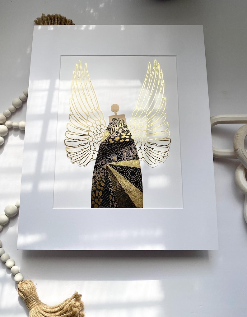 May include: A framed print of a gold angel with intricate patterns and designs. The angel has large wings and a body made of various textures and shapes.