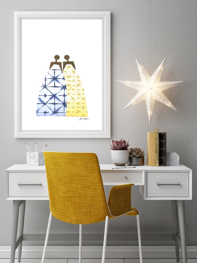May include: A framed print of a watercolor illustration of two figures wearing patterned dresses. The dress on the left is blue and white, and the dress on the right is yellow and white. The print is hanging on a white wall above a white desk with a yellow chair.