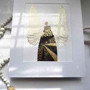 May include: A gold and black angel with wings made of gold foil. The angel is standing on a white background. The artist's signature is in the bottom right corner.