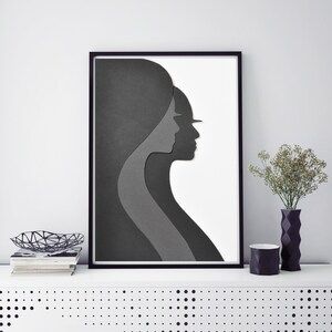 May include: Black and white framed print of two paper cut-out profiles of women facing each other.