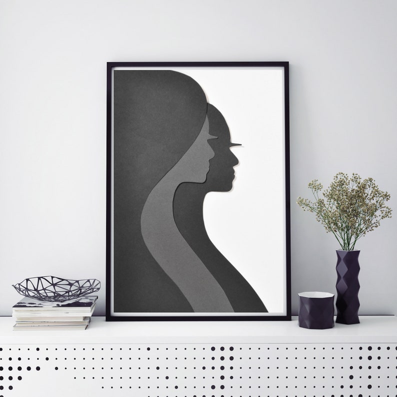 May include: Black and white framed print of two paper cut-out profiles of women facing each other.