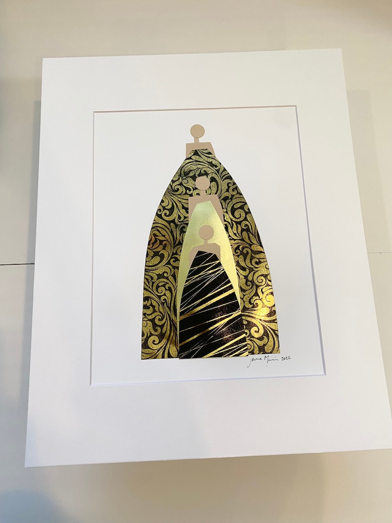Pu&ograve; includere: Una stampa artistica incorniciata con un design astratto in oro e nero di tre figure. Le figure sono sovrapposte, con la figura in basso che indossa un abito nero e le due figure in alto che indossano abiti dorati. La stampa &egrave; firmata "Jane Marin 2022".
