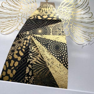 May include: A black and gold angel with wings made of gold leaf. The angel's body is made of a patchwork of different black and gold patterns. The angel is signed "Jeno Mai" in the bottom right corner.