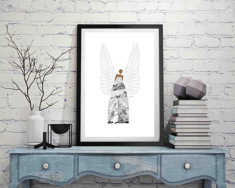 Puede incluir: Una impresi&oacute;n enmarcada en negro de un &aacute;ngel estilizado con alas blancas y un vestido estampado en blanco y negro. La impresi&oacute;n est&aacute; colgada en una pared de ladrillo blanco sobre una c&oacute;moda azul.
