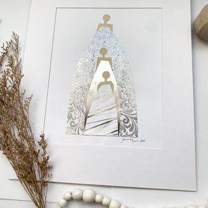 May include: A white matted print of a gold and silver abstract art piece depicting three figures standing on top of each other. The figures are outlined in gold and the background is a silver patterned design. The artist's signature and the year 2021 are in the bottom right corner of the print.