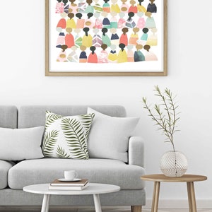 May include: A framed print of a colorful abstract art piece featuring a crowd of people in various shades of pink, blue, green, yellow, and orange. The print is set against a white background and framed in a light wood frame.