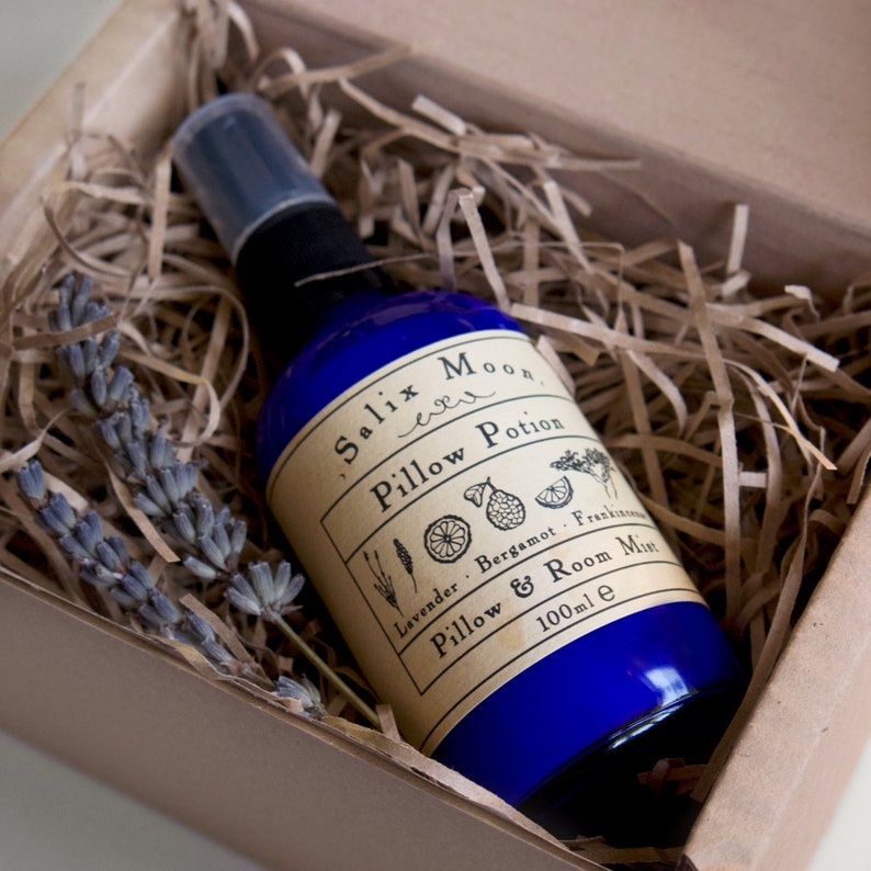 May include: A blue glass bottle with a spray nozzle, filled with a clear liquid. The bottle has a label that reads "Salix Moon Pillow Potion Lavender - Bergamot - Frankincense Pillow & Room Mist 100ml e".
