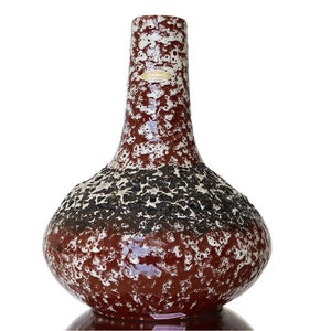 Può includere: Un vaso in ceramica marrone e bianco con una superficie testurizzata. Il vaso ha una base larga e un collo stretto. Il vaso è contrassegnato da un'etichetta che recita "Kerama Germany".