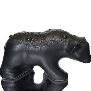 May include: A black ceramic bear figurine with a textured surface. The bear is standing on all fours and has a slightly tilted head.