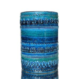 May include: A cylindrical ceramic vase with a textured surface. The vase features bands of turquoise, teal, and blue with geometric and floral patterns. The vase is approximately 30 cm tall.