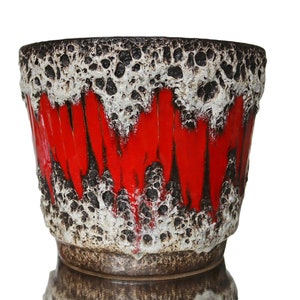 Può includere: Un vaso da fiori in ceramica rosso e marrone con una glassa testurizzata, simile alla lava. Il vaso ha un'ampia apertura rotonda e una base leggermente svasata.