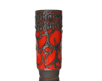May include: A red ceramic vase with a black and green floral design. The vase is tall and cylindrical.