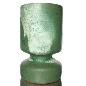 Op de afbeelding: Een groene en witte keramische vaas met een gespikkeld glazuur. De vaas heeft een brede basis en een smalle hals.