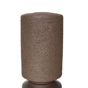 Peut inclure: Objet cylindrique en céramique marron avec une surface texturée. L'objet a un dessus arrondi et repose sur une base plus petite, marron foncé. La forme générale est un design simple mais élégant.