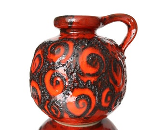 Puede incluir: Un jarrón de cerámica rojo y negro con un patrón de espiral. El jarrón tiene un asa y un cuerpo redondo.
