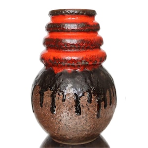 Può includere: Un vaso in ceramica con base bulbosa e collo cilindrico. La sezione superiore è di un rosso vibrante, che sfuma in un marrone scuro con accenti gocciolanti. La base è marrone strutturato.