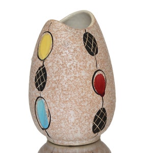 Könnte beinhalten: Eine Keramikvase mit einem gesprenkelten braunen Überzug und einem geometrischen Muster aus schwarzen, roten, gelben und blauen Kreisen.