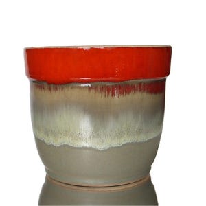 May include: A ceramic planter with a red rim and a light brown, green, and white glaze. The planter is round and has a wide base.
