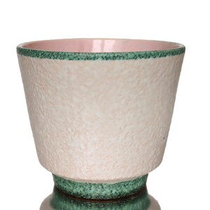 Peut inclure: Un pot en céramique avec un extérieur texturé blanc cassé. Le bord est bordé d'une bande verte et l'intérieur est rose. La base présente également une bande verte. Ce pot décoratif convient aux plantes d'intérieur.