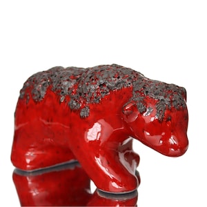 May include: A red ceramic bear figurine with a textured surface. The bear is standing on all fours and has a glossy finish.