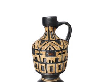 May include: A black and brown ceramic vase with a geometric design. The vase has a wide base and a narrow neck with a handle.