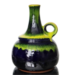 Op de afbeelding: Een blauwe en groene keramische vaas met een handvat. De vaas heeft een rond lichaam en een lange, smalle hals.