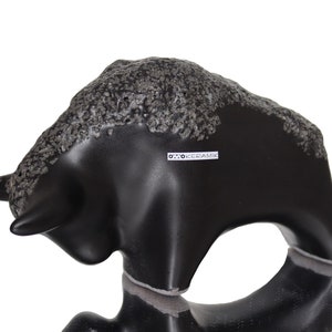 May include: Black ceramic bull figurine with a textured surface. The figurine is made by Otto Keramik.